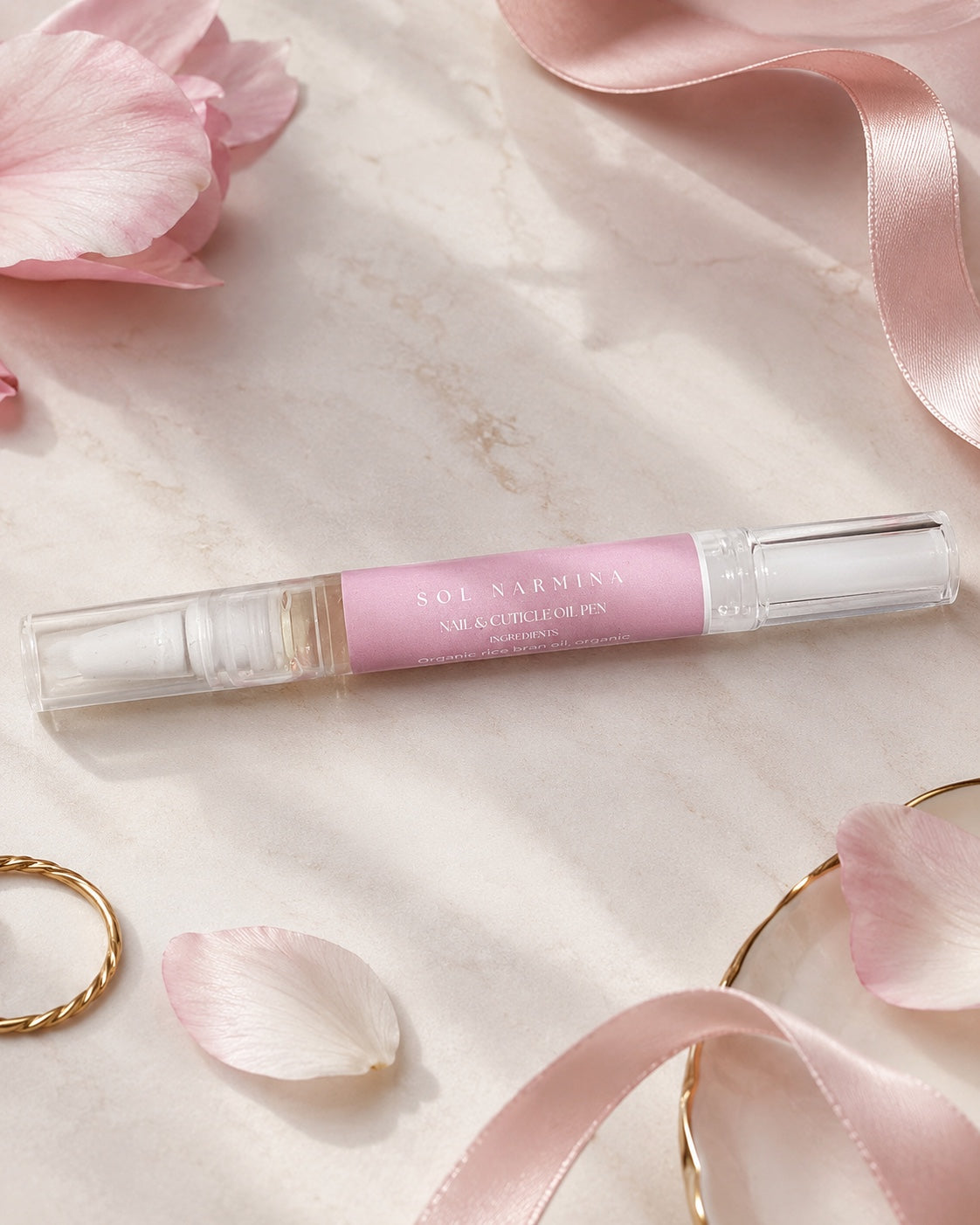 Sol Narmina Nail & Cuticle Oil Pen flat lay with pink ribbon and petals